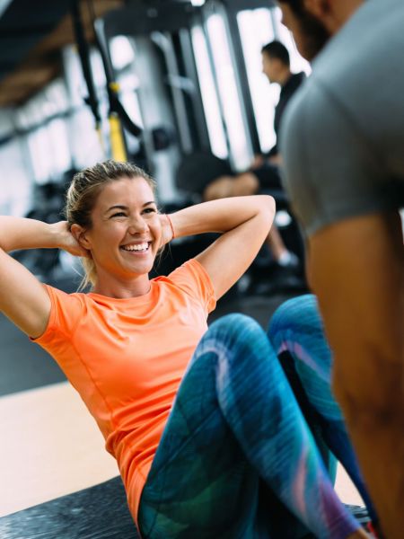 Young beautiful woman doing exercises with personal trainer in gym